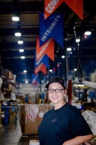 Versa Pak employee with company values flags in background of manufacturing floor.